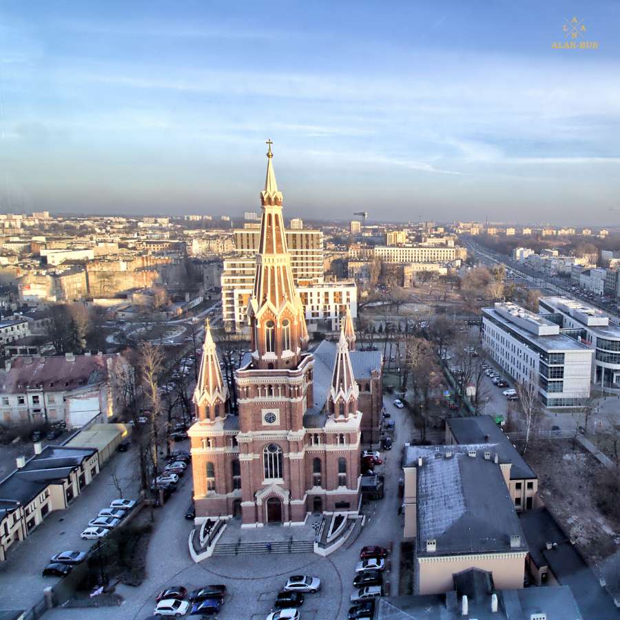 Kościół Najświętszego Imienia Jezus w Łodzi – neogotycka świątynia jezuitów z wysoką wieżą, sfotografowana z lotu ptaka na tle miejskiej panoramy, w regionie obsługiwanym przez ALAN-BUS
