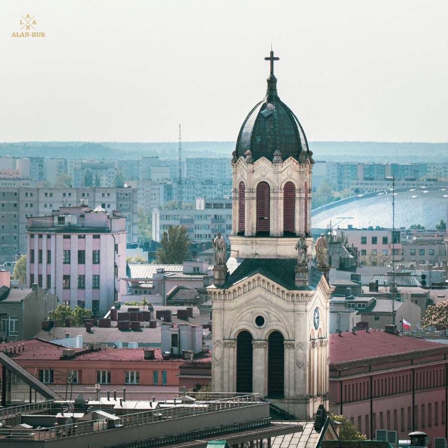 Kościół Podwyższenia Świętego Krzyża w Łodzi z monumentalną wieżą i kopułą, widoczny na tle miejskiej zabudowy – charakterystyczny punkt na trasach ALAN-BUS