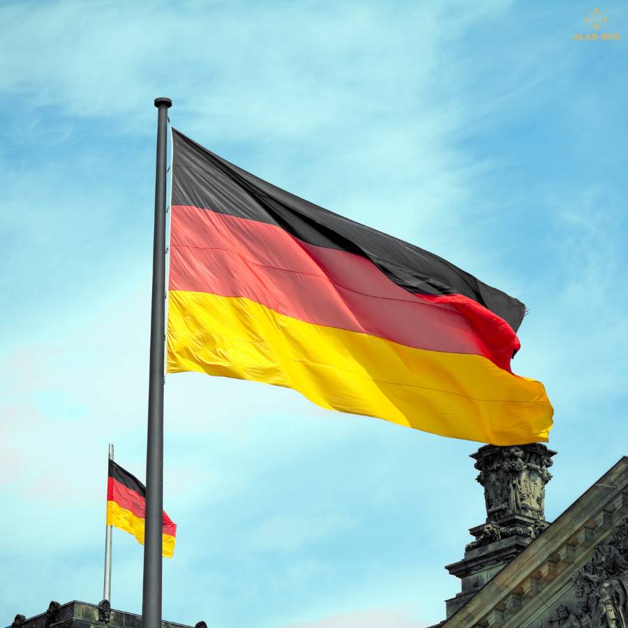 Powiewająca na wietrze flaga Niemiec na tle nieba, przy historycznym budynku w Berlinie