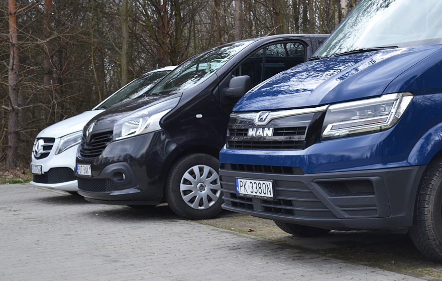 Trzy nowoczesne, ciemne busy pasażerskie Alan-Bus na parkingu firmy