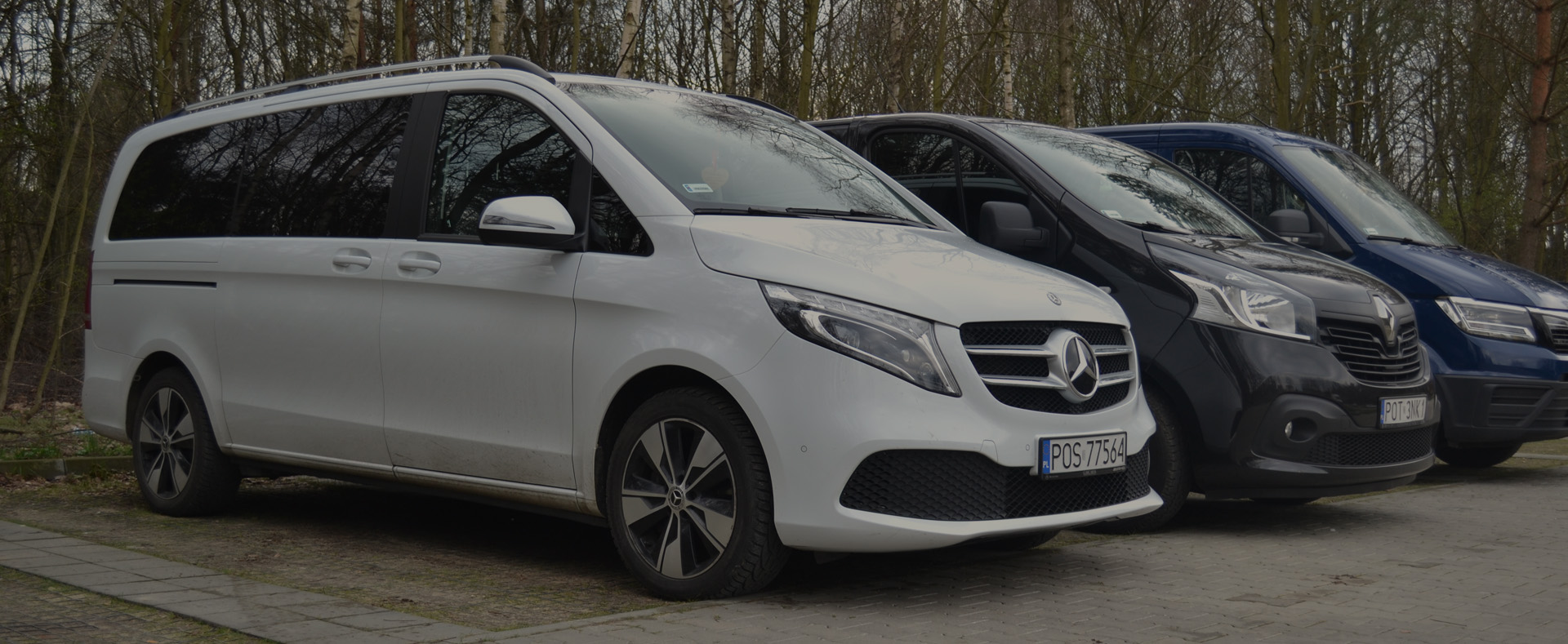 Biały, komfortowy bus pasażerski Mercedes zaparkowany obok innych pojazdów z floty